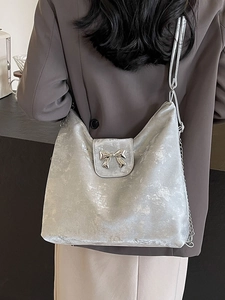 Sac fourre-tout gris argenté avec nœud métallique porté par un mannequin en café