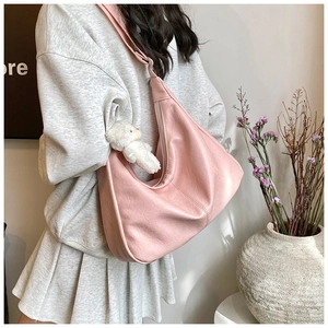 Détail de la texture cuir rose du sac hobo avec un porte-clés petit ours blanc