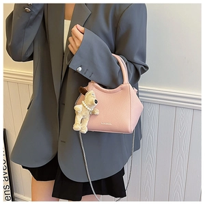 Détail du sac seau rose en cuir grainé avec bandoulière chaîne et porte-clés peluche