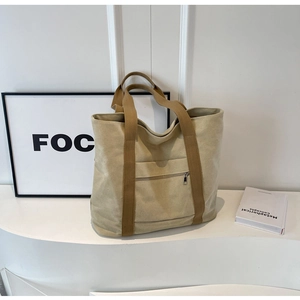 Detail of canvas tote bag with brown straps and functional front zipper pocket