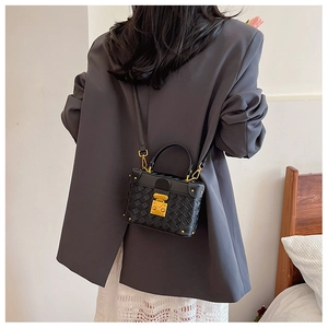 Detail of black woven bucket bag with gold rivets and lock shown on a model