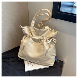 Détail du sac seau en toile blanc cassé avec cordon de serrage, poche avant et étiquette