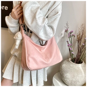 Vue détaillée d'un sac hobo rose avec un charm ours en peluche et une finition en cuir texturé