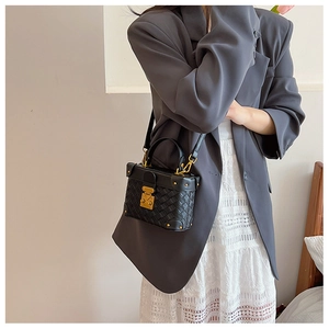 Detail of black woven texture handbag with vintage gold buckle on a model's outfit