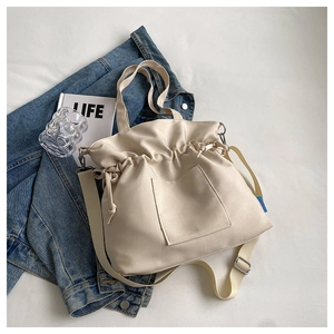 Vue à plat du sac cabas en toile crème avec cordon de serrage et détails plissés