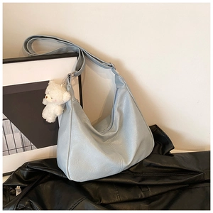 Détail du sac à bandoulière croissant bleu clair avec un pendentif ours en peluche