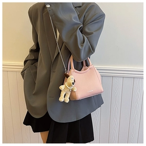 Gros plan du sac seau rose grainé avec chaîne argentée et charm de chien en peluche