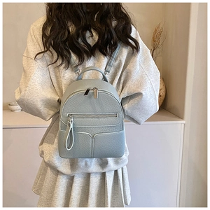 Close-up of light blue pebble leather mini backpack with metal zippers and slim straps