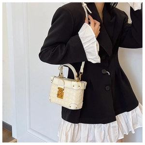 White woven box bag with gold metal clasp shown as a crossbody on a stylish model