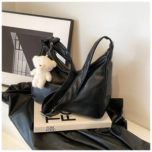 Détail du sac hobo en cuir noir souple avec plis naturels et charmant pendentif ours en peluche