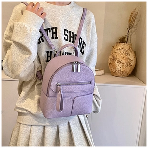 Lifestyle view of a purple mini faux leather backpack with litchi grain and silver zippers