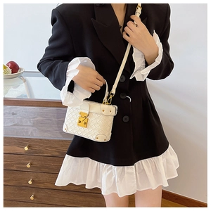 Close-up of a white woven texture bucket bag held by a model in a stylish blazer dress