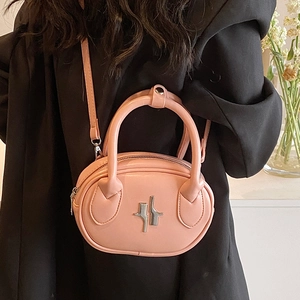 Pink oval leather handbag with silver logo and chain strap worn with black blazer