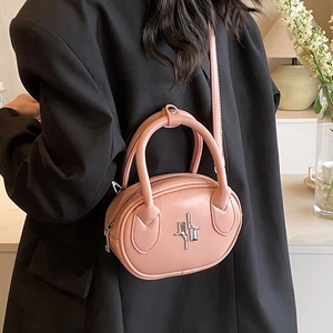 Pink oval chain shoulder bag with geometric metal decor worn with a black suit