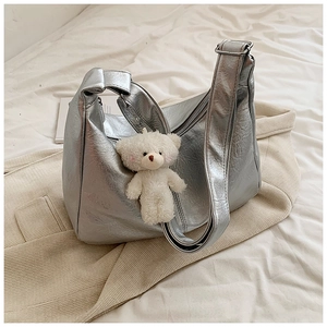 Détail du sac hobo argenté avec texture froissée et breloque ours en peluche blanc