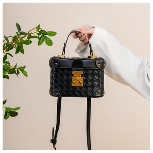 Close-up of black woven box bag featuring vintage gold clasp and metallic rivet details