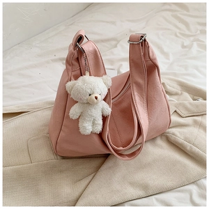 Détail d'un sac à bandoulière en similicuir plissé rose avec charmant ours en peluche