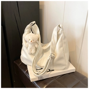 Détail de la texture plissée du sac à bandoulière blanc en cuir PU avec ours en peluche