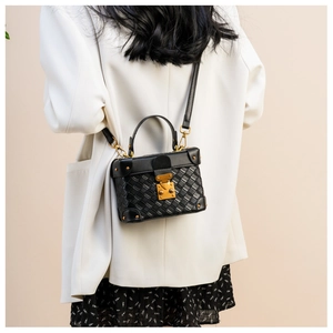 Detail of black woven leather box bag with gold-tone hardware and top handle strap