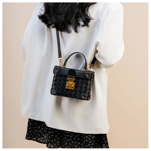 Crossbody view of black woven box bag with gold buckle and leather shoulder strap