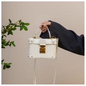 Chic white woven bucket bag with gold stud corners and metallic lock on a model