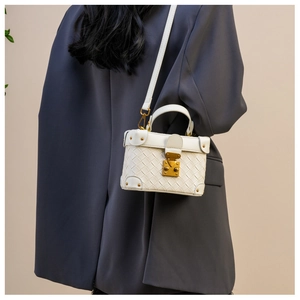 Detailed view of white woven texture bucket bag with gold hardware on a gray blazer model