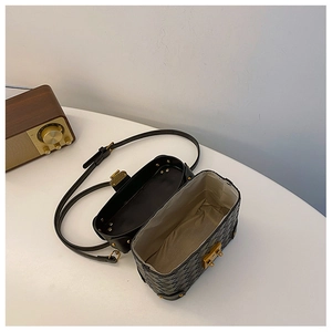 Detail view of black woven bucket bag with gold lock and spacious interior lining