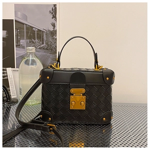 Detail of a black woven leather box bag featuring vintage gold metal locks and studs
