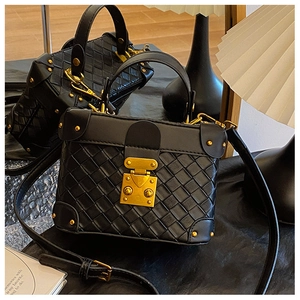 Detailed view of black woven box bag with gold rivets and vintage metal lock closure