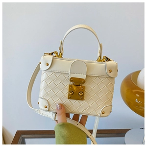 Detail of white woven textured box bag with gold metal clasp and top handle