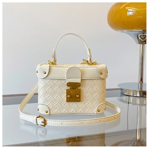 Detail of white woven leather box bag with gold lock and vintage metal corners