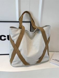 Minimalist beige and brown canvas tote bag with contrast webbing straps in a bright room