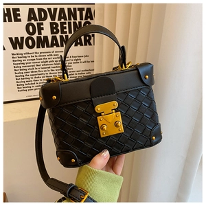 Close-up of black woven leather bucket bag featuring a gold metal buckle and sturdy handle