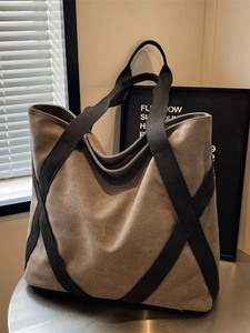 Olive green canvas tote bag with black woven straps in a minimalist indoor studio setting
