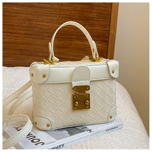 Close-up of white woven bucket bag with gold hardware and reinforced metal corners
