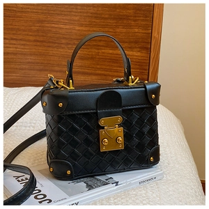 Detail of a black woven leather bucket bag with gold rivets and vintage metal clasp