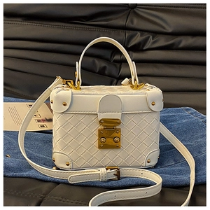 Detail of white woven box bag with golden metal buckle and metallic rivet accents