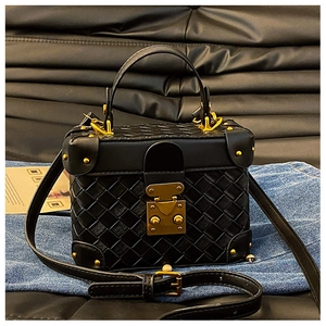 Detail of black woven box bag featuring gold hardware and metallic corner protectors
