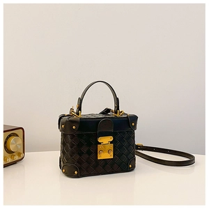 Detail of a black woven mini trunk bag with gold hardware and retro box design