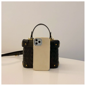 Detailed shot of woven leather bucket bag with gold rivets and smartphone for size reference
