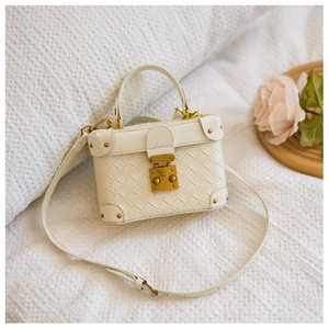 Detail of cream woven bucket bag with vintage gold metal clasp and corner rivets