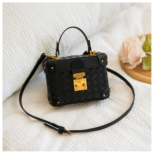 Detail of black woven trunk bag featuring golden metallic rivets and a vintage clasp