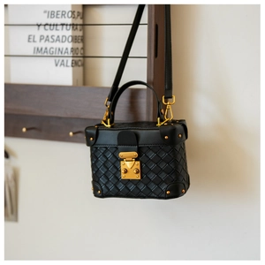 Close-up of black woven leather box bag with vintage gold hardware and clasp detail
