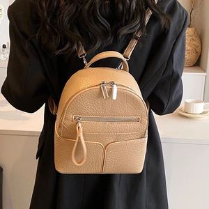 Mini camel PU leather backpack with lychee grain and silver zippers on a female model