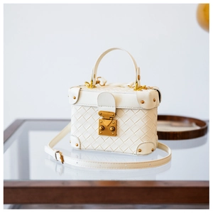 Detail of white woven box bag featuring vintage gold lock and protective metal corners