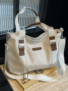 Minimalist white canvas tote bag with brown leather details on a decorative book