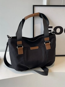 Large black canvas tote bag with brown leather trim and adjustable crossbody strap