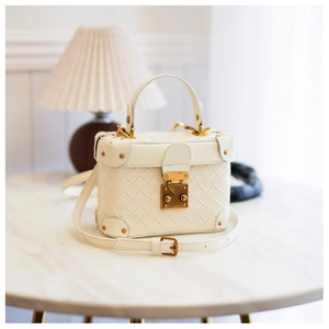 Close-up of cream woven trunk bag with golden vintage hardware and rivet detail