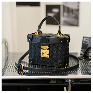 Close-up of black woven leather bucket bag with gold hardware on a metal shelf
