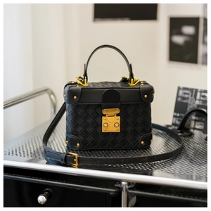 Close-up of black woven leather bucket bag with gold rivets and vintage lock